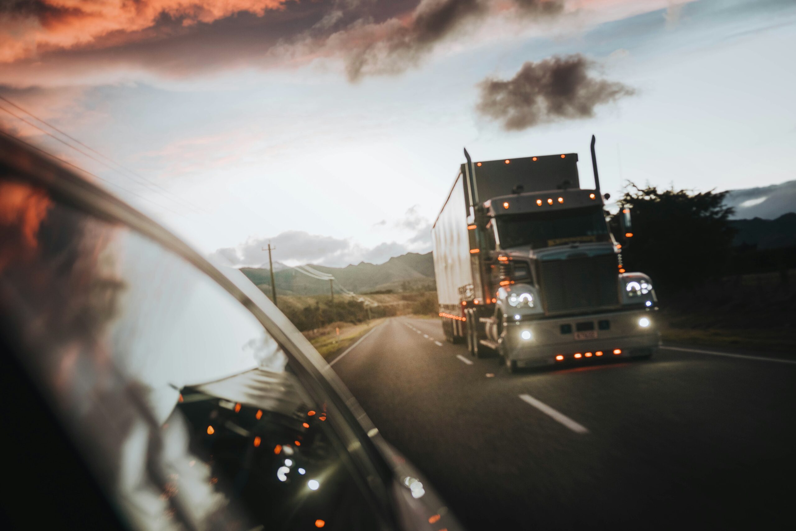 image of a semi truck driving on the road at dusk